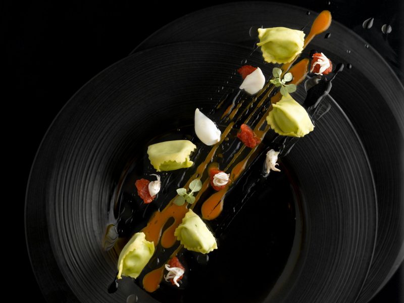 Agnolotti di basilico e ricotta, nero di seppia e zafferano composta di pomodori e calamaretti al vino bianco