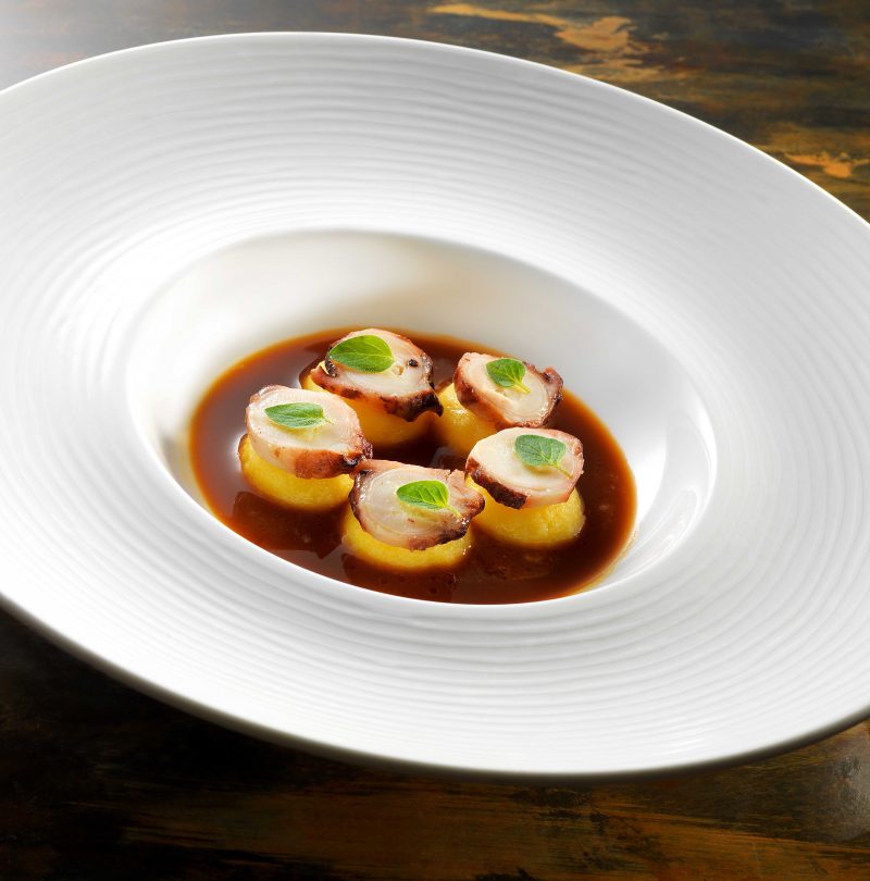Bottoni di olio e lime con salsa cacciucco e polpo alla brace